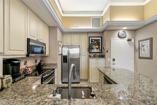 kitchen featuring light stone countertops, ornamental molding, cream cabinets, stainless steel appliances, and a sink