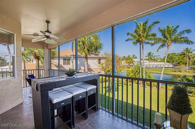 sunroom / solarium with ceiling fan and a water view