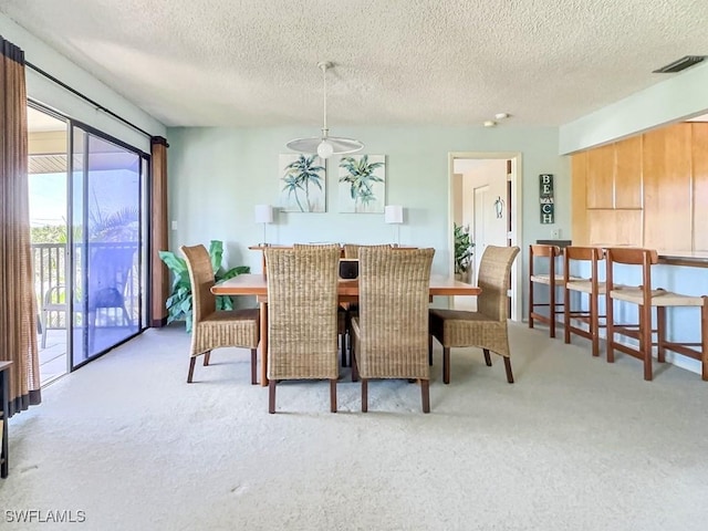 carpeted dining space featuring a textured ceiling