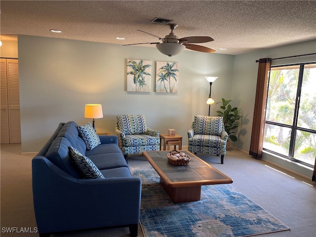 carpeted living room with ceiling fan and a textured ceiling