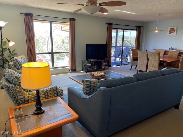 carpeted living room featuring ceiling fan and a textured ceiling