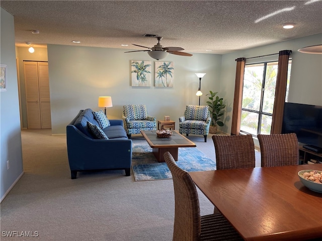 carpeted living room featuring ceiling fan and a textured ceiling