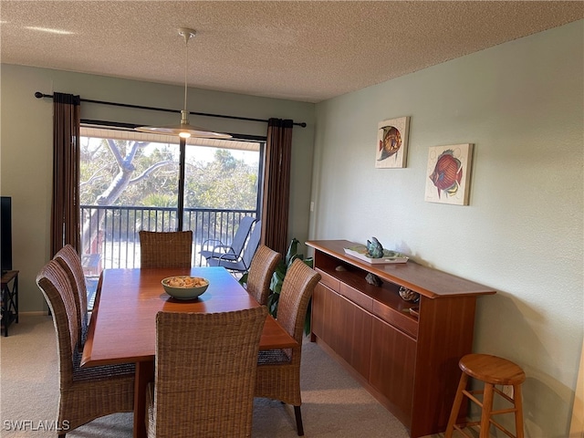 dining area featuring light colored carpet and a textured ceiling