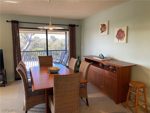 dining area featuring light carpet and a textured ceiling