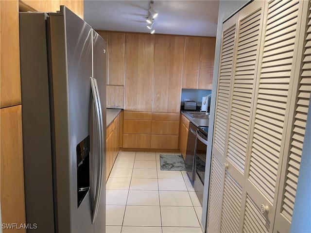 kitchen with stainless steel appliances, rail lighting, light tile patterned floors, and wooden walls