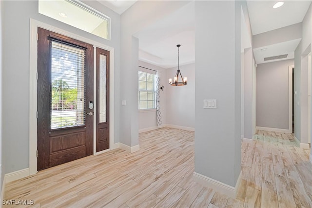 entrance foyer with light hardwood / wood-style flooring, a chandelier, and plenty of natural light