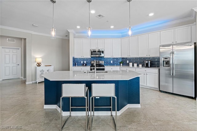 kitchen with white cabinets, appliances with stainless steel finishes, a kitchen island with sink, and sink