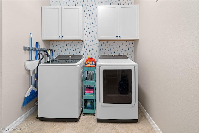 clothes washing area featuring cabinets, separate washer and dryer, and light tile patterned floors