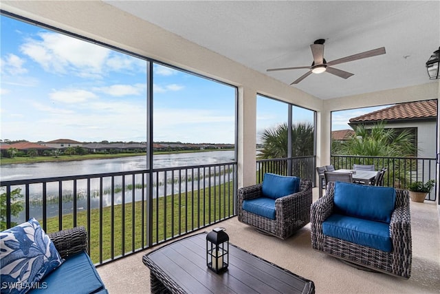 sunroom with ceiling fan and a water view