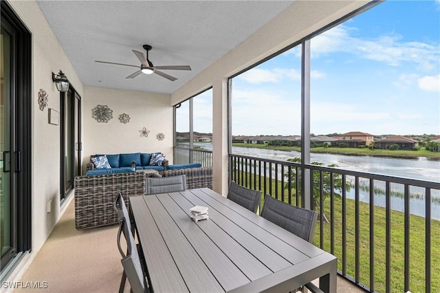 sunroom featuring ceiling fan and a water view