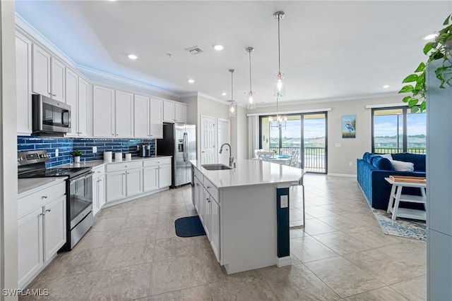 kitchen with stainless steel appliances, sink, a center island with sink, white cabinetry, and hanging light fixtures