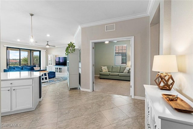 kitchen with light carpet, ceiling fan, crown molding, white cabinetry, and hanging light fixtures