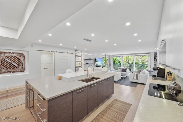 kitchen featuring expansive windows, a spacious island, sink, a barn door, and dark brown cabinetry