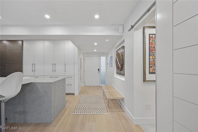 corridor with a barn door and light hardwood / wood-style floors