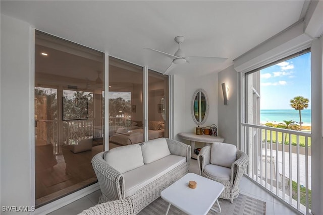 sunroom featuring ceiling fan and a water view