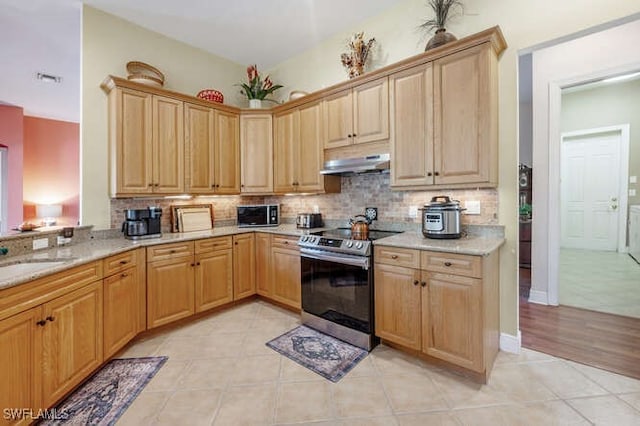 kitchen featuring light stone countertops, backsplash, light tile patterned flooring, stainless steel range with electric stovetop, and sink