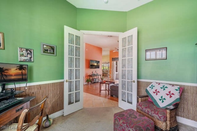 living area featuring ceiling fan, french doors, wooden walls, and light tile patterned floors