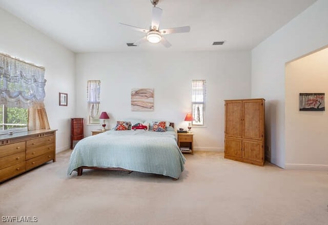 bedroom with light carpet, a ceiling fan, visible vents, and baseboards