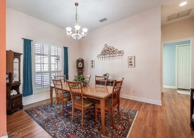 dining area featuring wood-type flooring and a chandelier