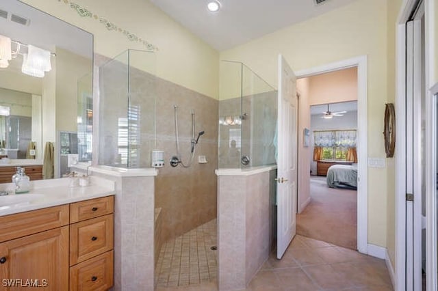 bathroom featuring ceiling fan, tile patterned flooring, a tile shower, and vanity