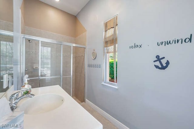 bathroom featuring a tile shower, vanity, and baseboards