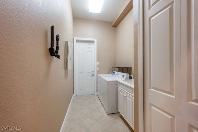washroom with washing machine and dryer, baseboards, cabinet space, and a textured wall