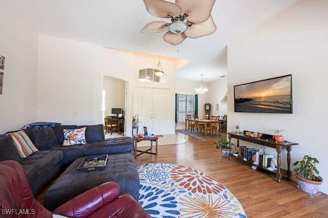 living room with ceiling fan with notable chandelier and hardwood / wood-style floors