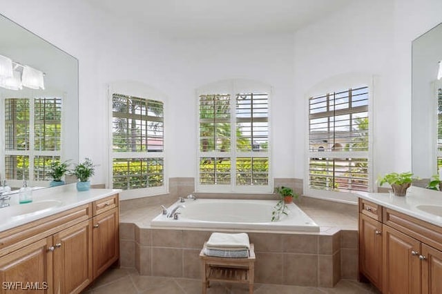 bathroom featuring a bath, two vanities, tile patterned flooring, and a sink