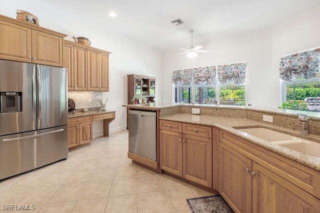 kitchen featuring light stone counters, a ceiling fan, a sink, light tile patterned floors, and appliances with stainless steel finishes