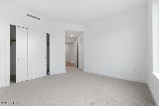 unfurnished bedroom with a closet and light colored carpet