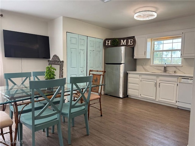 kitchen featuring sink, dishwasher, stainless steel refrigerator, and white cabinets