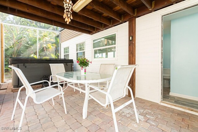 view of patio / terrace featuring a hot tub and glass enclosure