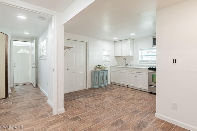 kitchen with stainless steel range with electric stovetop, sink, and white cabinets