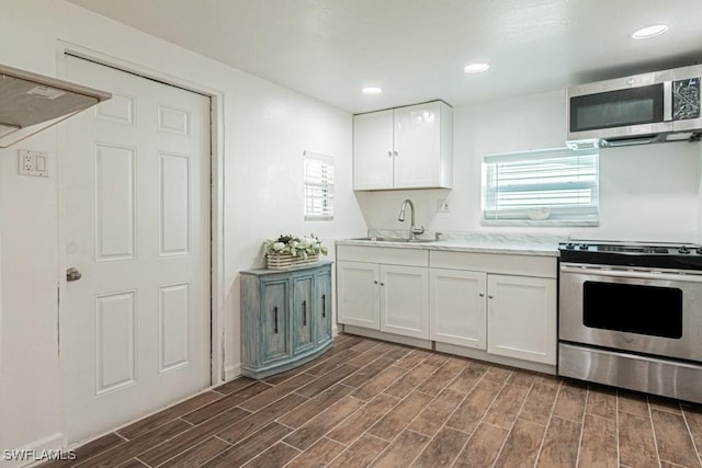 kitchen with stainless steel appliances, white cabinetry, and sink