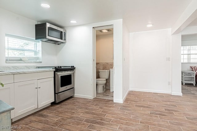 kitchen with tile walls, light stone countertops, stainless steel appliances, and white cabinets