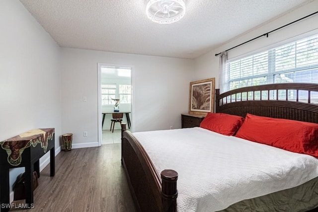 bedroom with multiple windows, hardwood / wood-style floors, and a textured ceiling