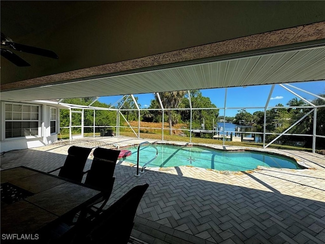 view of pool featuring a patio area, ceiling fan, a water view, and glass enclosure