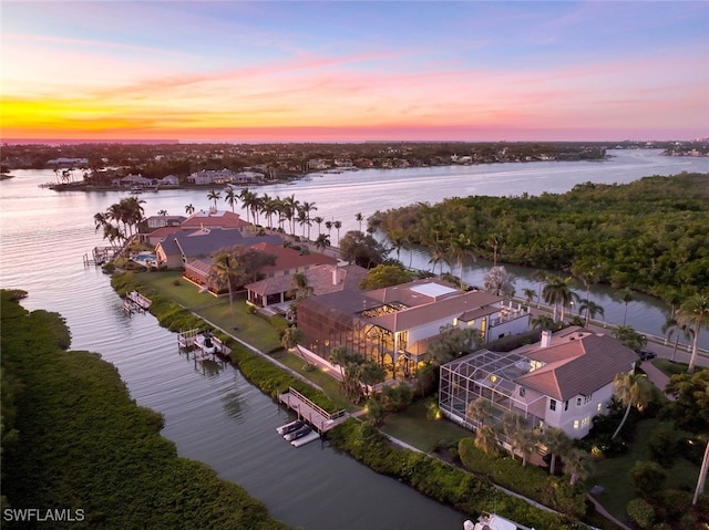 aerial view at dusk featuring a water view