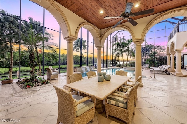 patio terrace at dusk featuring ceiling fan and a lanai