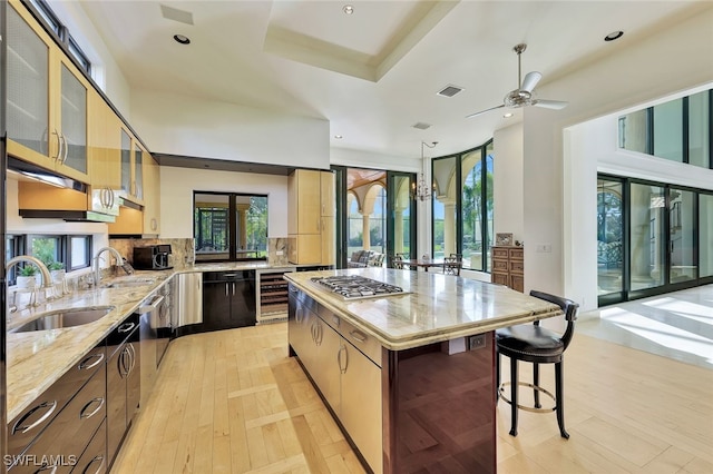 kitchen featuring backsplash, sink, stainless steel gas cooktop, a kitchen island, and beverage cooler