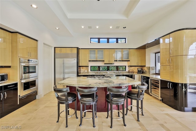 kitchen with a breakfast bar area, light stone countertops, a kitchen island, and stainless steel appliances