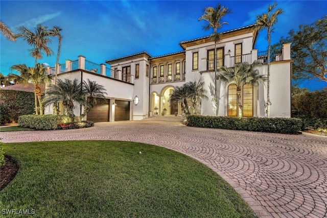 mediterranean / spanish-style home with a lawn, a garage, and a balcony