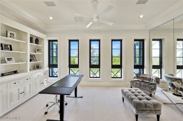 office area featuring ceiling fan, a healthy amount of sunlight, a raised ceiling, and light carpet