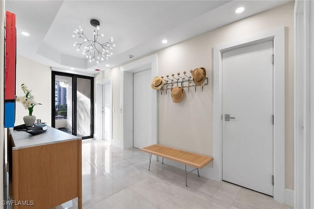 interior space with french doors, a raised ceiling, elevator, light tile patterned flooring, and a chandelier