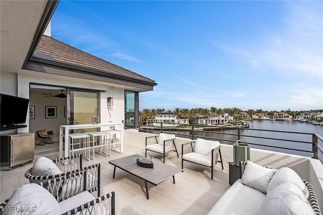 view of patio with an outdoor living space, a water view, and a balcony