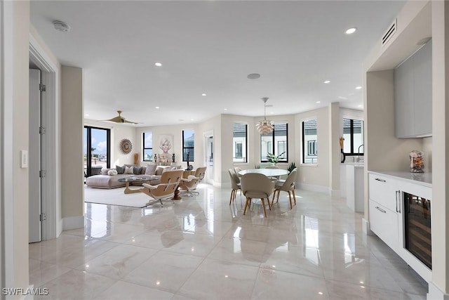 dining area with beverage cooler and ceiling fan with notable chandelier