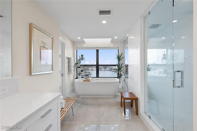 bathroom with vanity, separate shower and tub, a water view, and a skylight