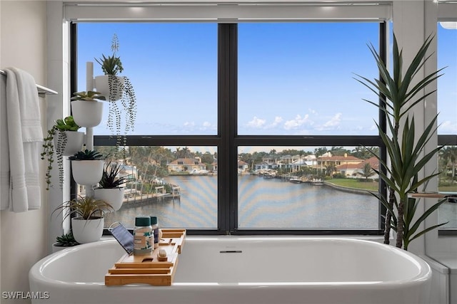 bathroom featuring a bathtub, a water view, and a healthy amount of sunlight