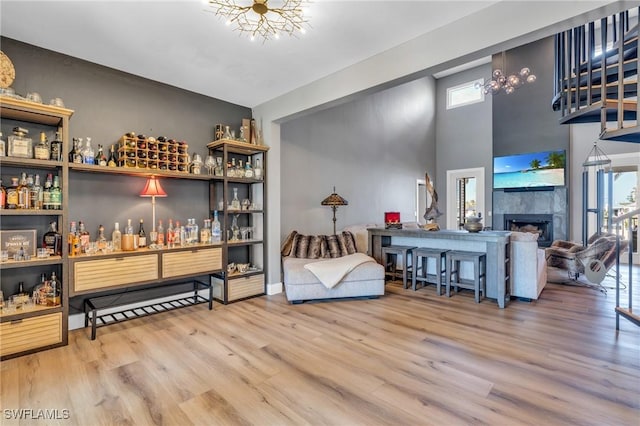 bar with a bar, a towering ceiling, wood finished floors, and a tile fireplace