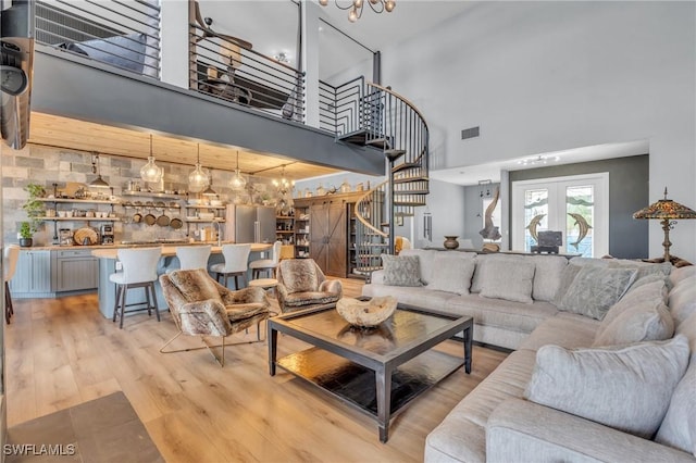 living room featuring light wood-style flooring, visible vents, french doors, stairway, and an inviting chandelier